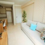 Spacious modern living room with a white couch, blue pillows, and a compact dining area.