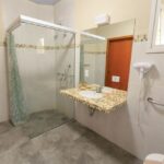 Spacious and accessible bathroom featuring a large glass shower, modern sink, and stylish decor.